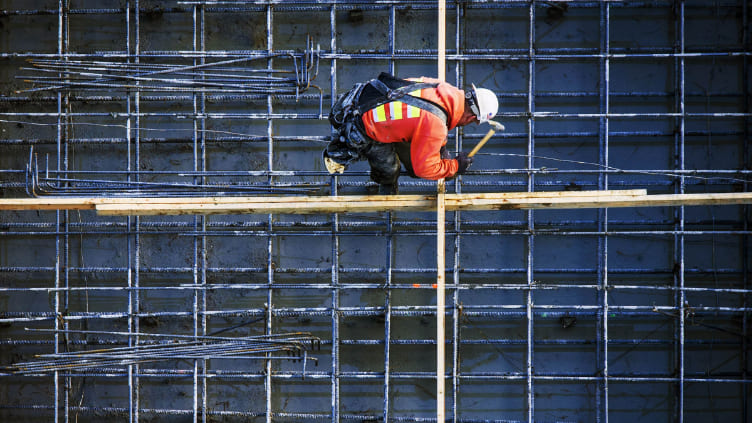 Construction worker working on a construction site surrounded by metal structure.