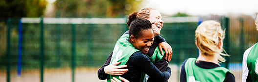 female team happily hugging in the field