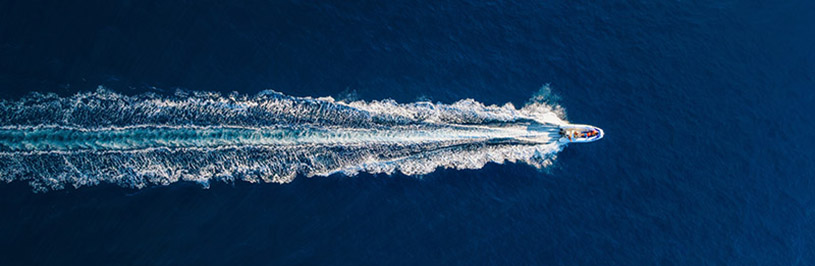 Ein elegantes kleines Schiff auf blauem Meer aus der Vogelperspektive.