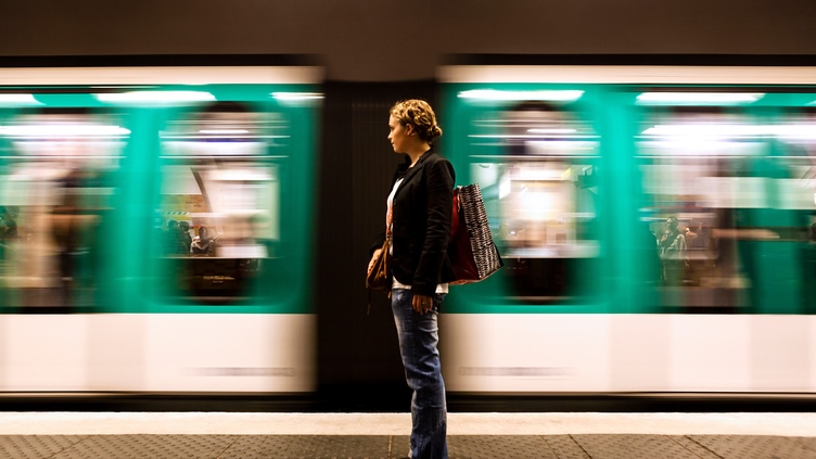 Person standing on a train platform as a high‑speed train passes, representing timing, progress and capturing investment momentum.