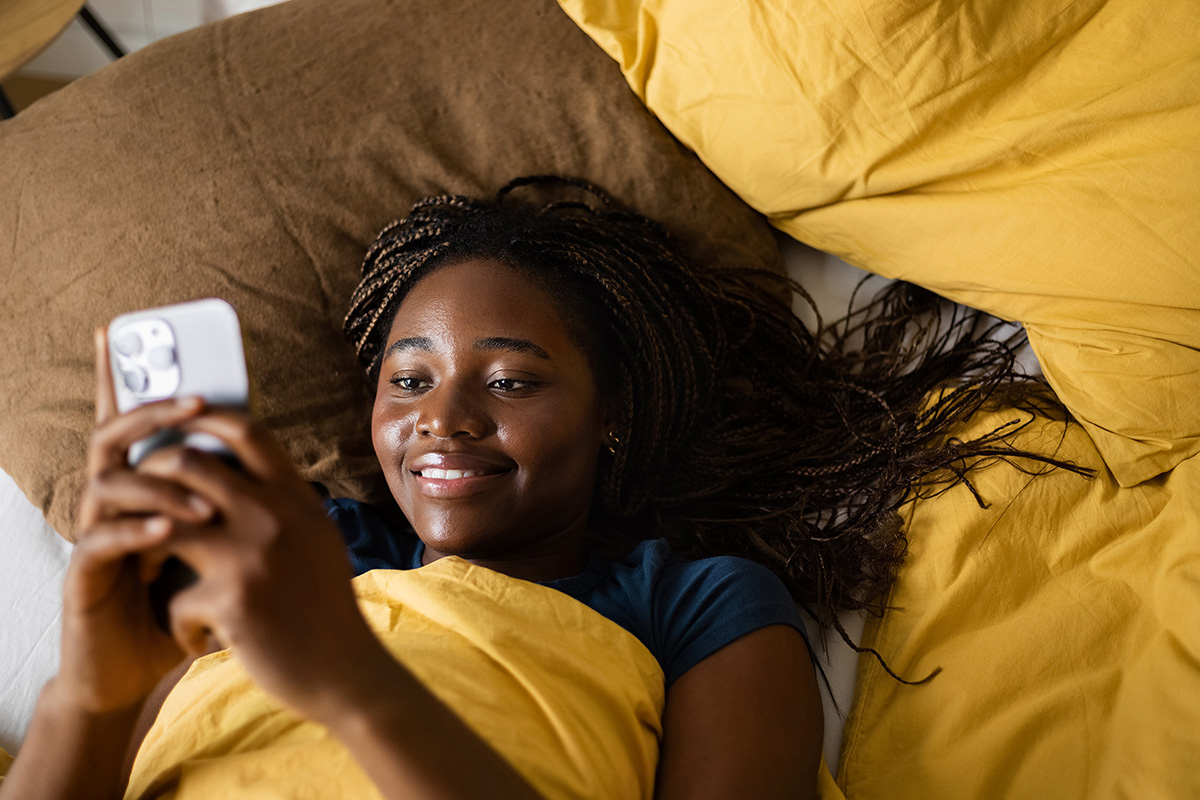 Frau im Bett schaut auf Handy
