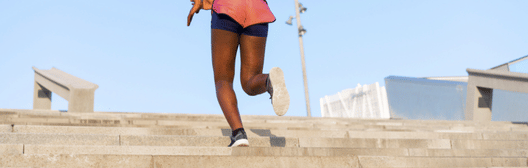 Person running up outdoor concrete steps under a clear blue sky