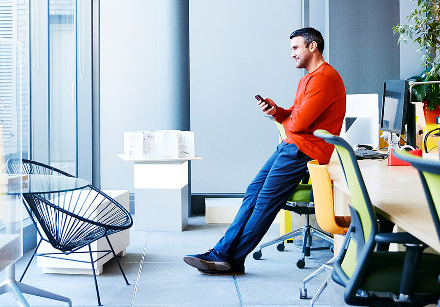 Eine Person sitzt in einem modernen Büro-Ambiente mit Blick auf große Glasfensterwand.