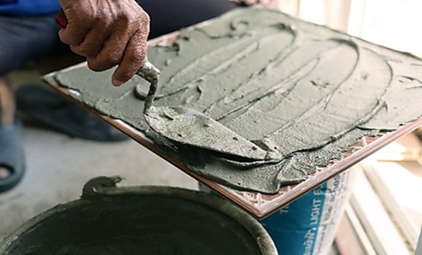 Hands applying and smoothing cement on a surface, symbolising the foundations of resilient portfolio construction.