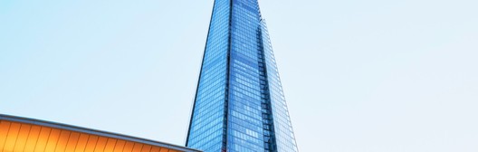 The Shard skyscraper rising above a golden curved rooftop against a clear sky in London