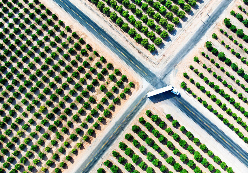 Aerial view of a truck traveling through an intersection surrounded by rows of trees