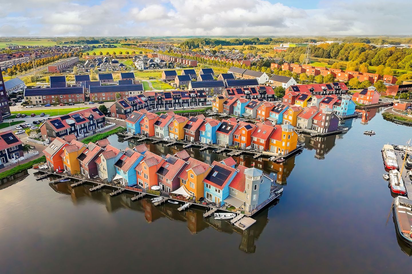 Aerial view of a waterfront residential community with rows of brightly colored houses along narrow canals