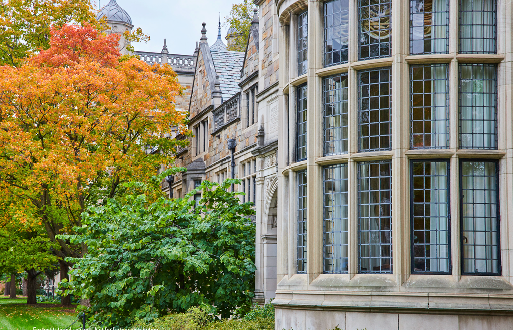 Historic stone building with large windows and autumn trees