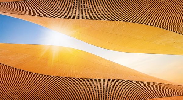 Abstract golden architectural curves with sunlight streaming through a central opening.
