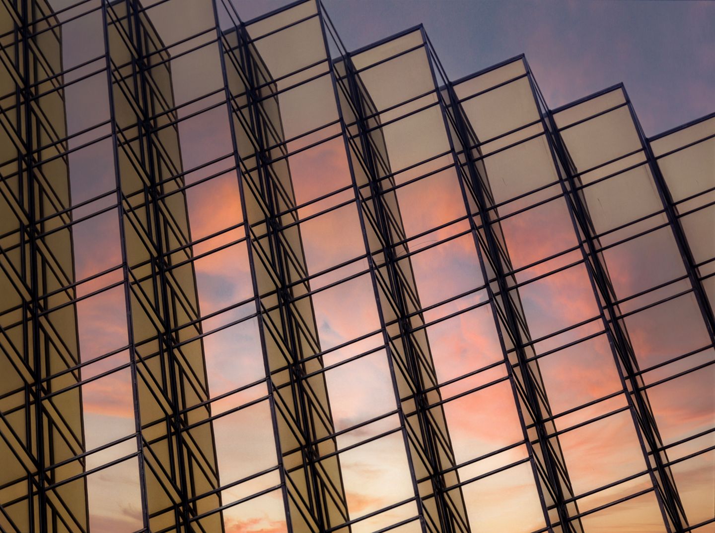 The sunset is reflected in the yellow glass surface of a modern building in Hong Kong. Low angle view.