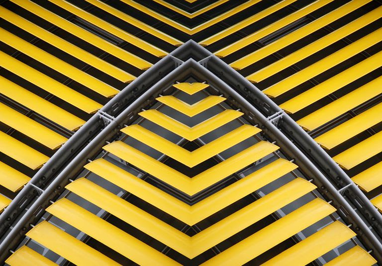 Geometric pattern of yellow and black building facade with diagonal lines and symmetrical angles