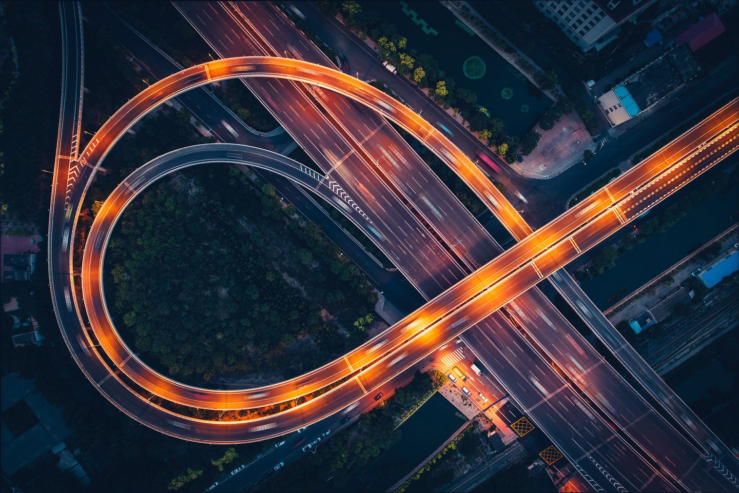 Aerial view of a highway interchange at night with looping overpasses forming curved patterns