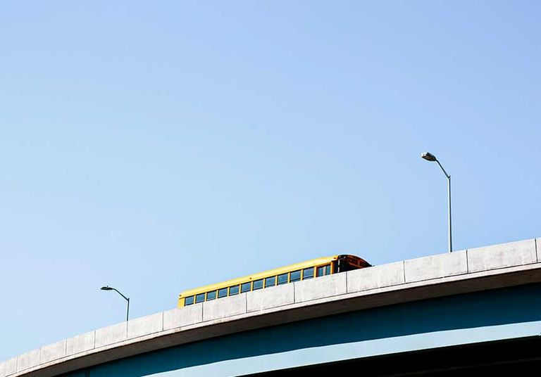 A yellow school bus crosses a bridge, representing the path to financial security through 403(b) retirement plans.