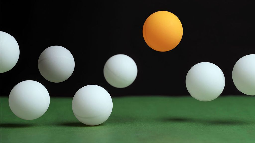 Ping pong balls jumping against a dark background