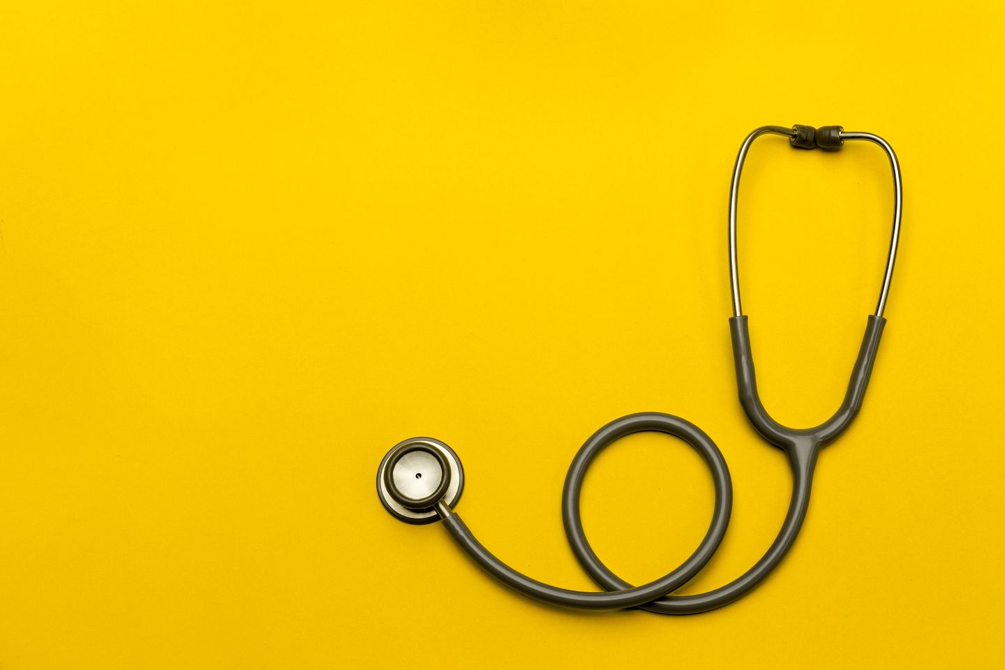 A stethoscope coiled on a bright yellow background