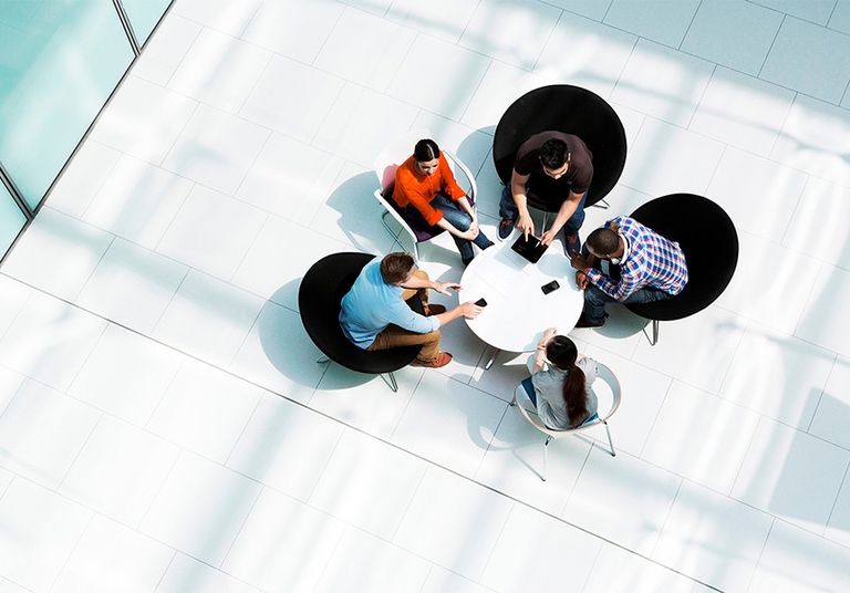 aerial view of five people sitting around a circular table in a modern, open space
