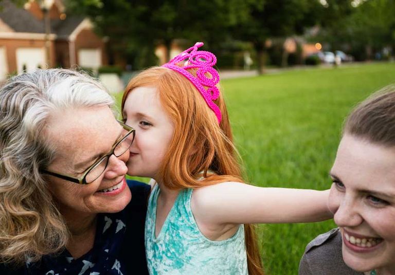 A woman and two girls share a loving moment in the grass, symbolizing the importance of fostering financial well-being through strong retirement planning.