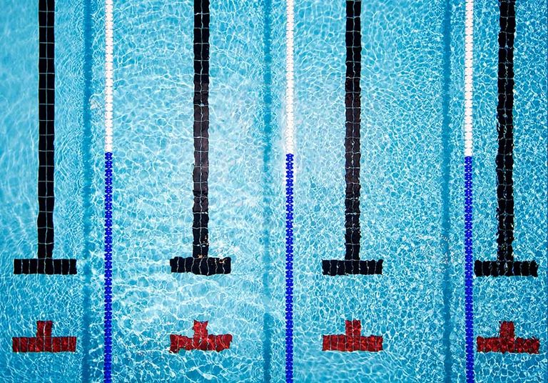 A clear swimming pool showcasing blue water and red lines that delineate the swimming lanes in parallel