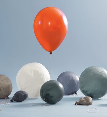 red balloon flying higher than the rest