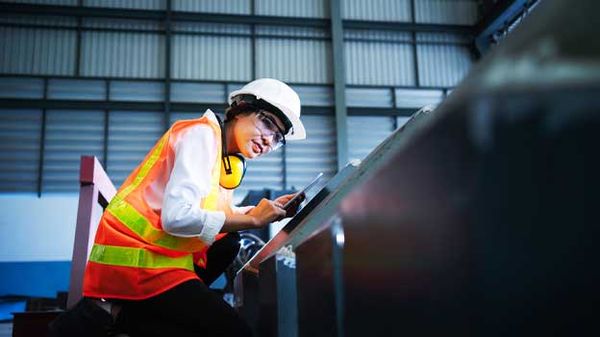 A woman in a hard hat and safety vest operates machinery, symbolizing the importance of planning for a secure retirement.