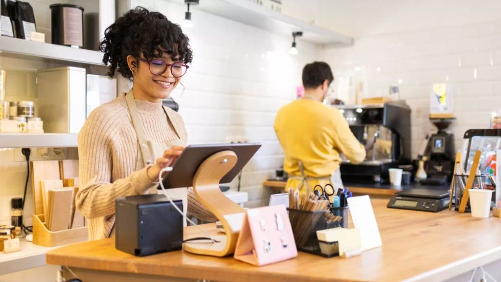 A female cashier and a male barista in a cafe​