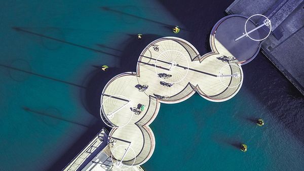 Aerial view of a pier featuring boats and people, with multiple circular bridges enhancing the scenic landscape