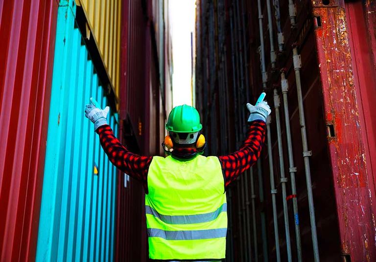 Worker wearing vest overseeing large storage units