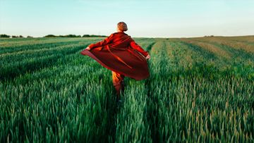 Woman dancing in field with red coat.