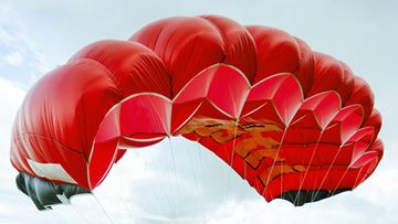Red parachute in sky.