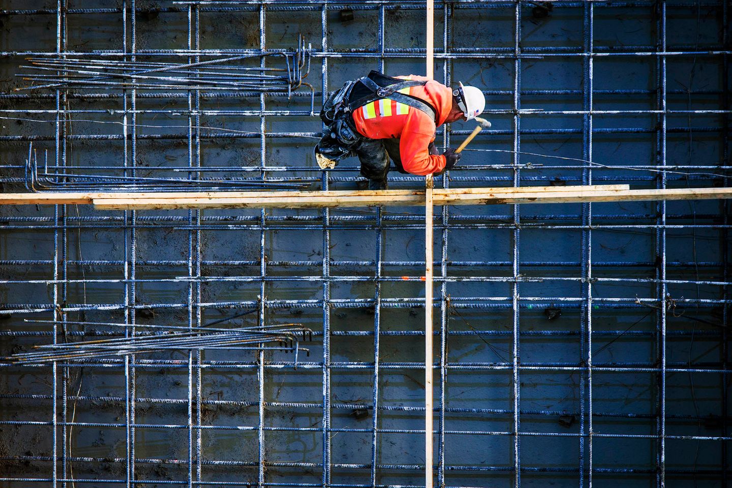 Construction worker in a high-visibility jacket and hard hat working at a construction site.