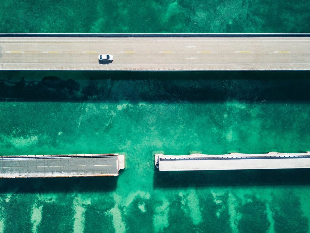 An image of two bridges, one is continuous with a car driving on it, the other is split