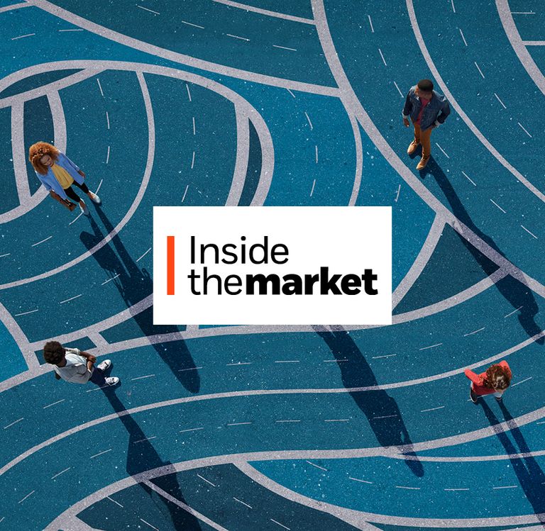 Aerial view of people walking across a blue surface covered with intersecting curved lines, casting long shadows.