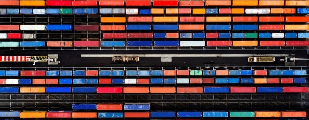 Overhead view of stacked shipping containers at a cargo terminal, illustrating global trade and transportation infrastructure