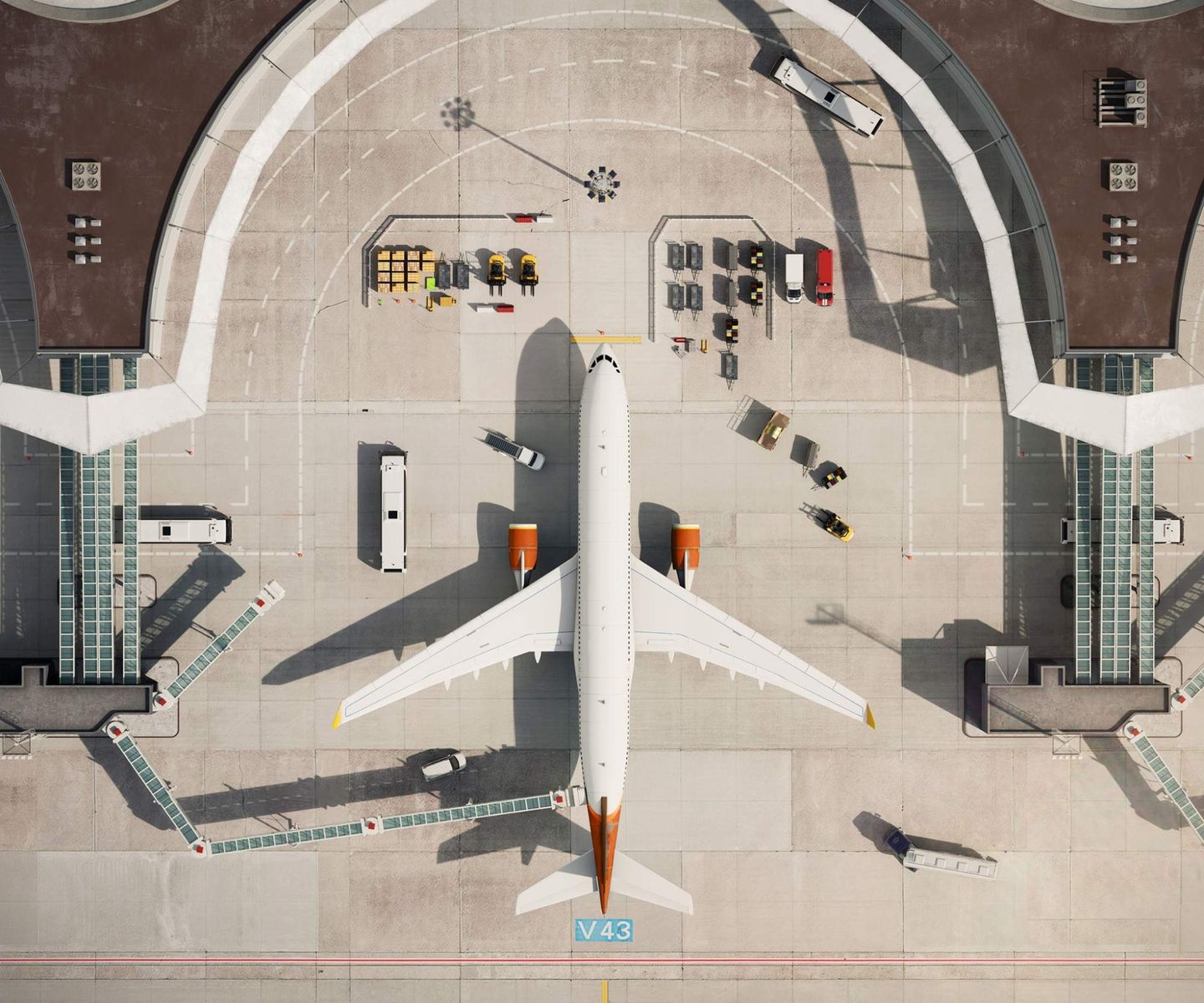 Aerial view of an airplane at an airport gate with ground crew, vehicles, and cargo operations.