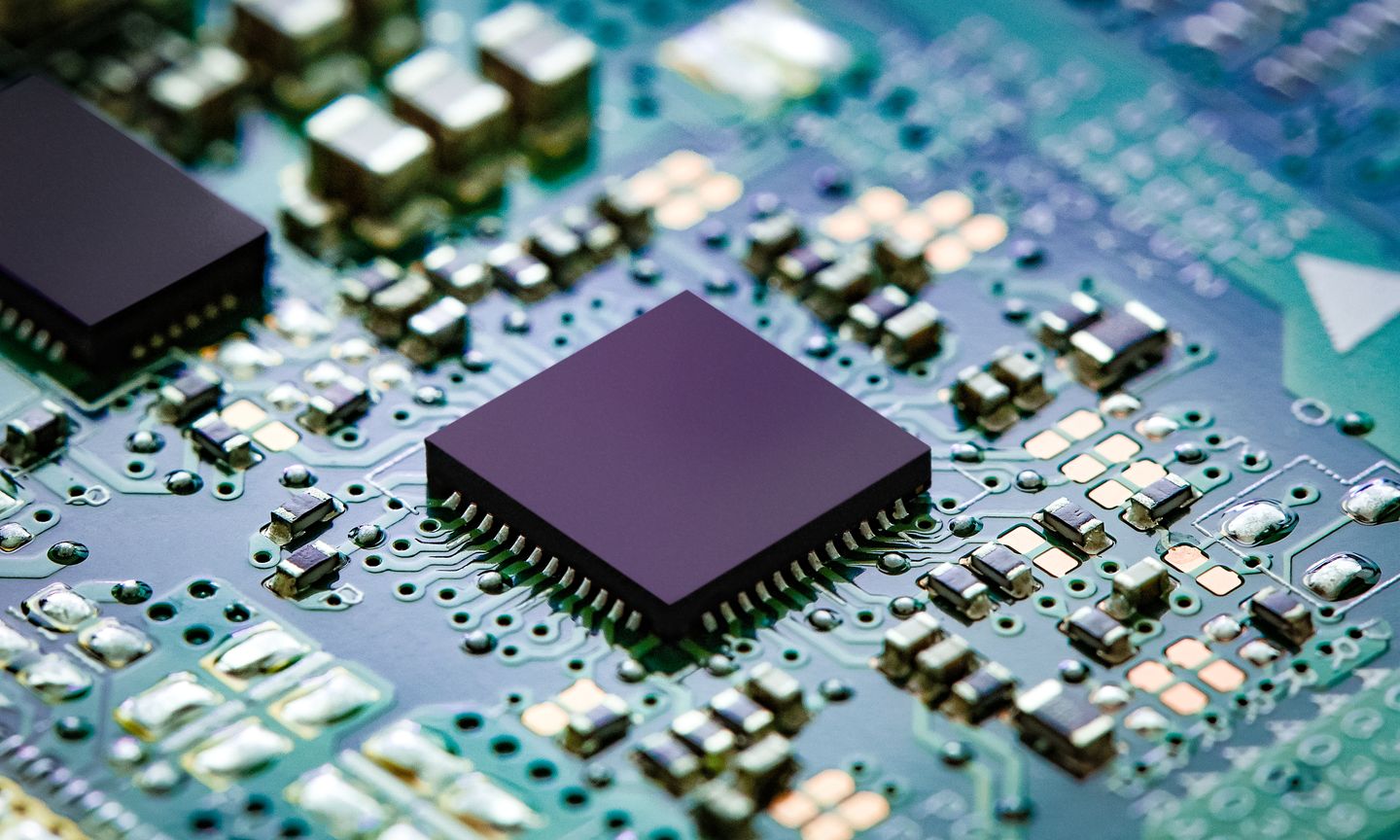 Close-up of a microchip on a circuit board with surrounding electronic components.