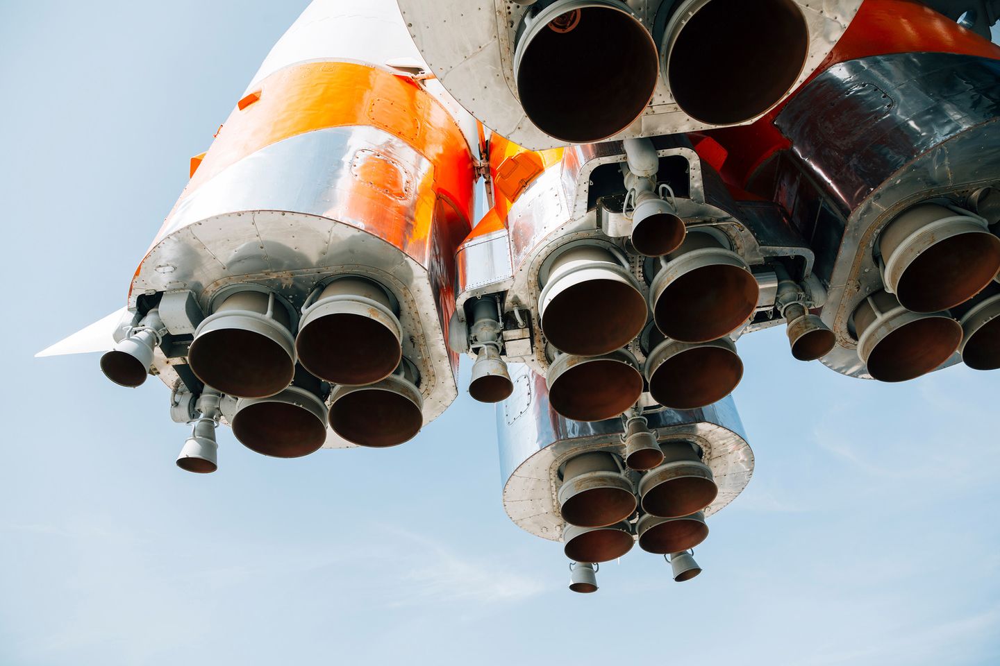 Bottom view of a rocket showing clustered large and small engine nozzles, with orange, white, and metallic sections on the body.